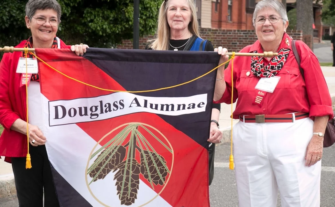 Three Douglass Alumnae hold a Douglass Alumnae Banner